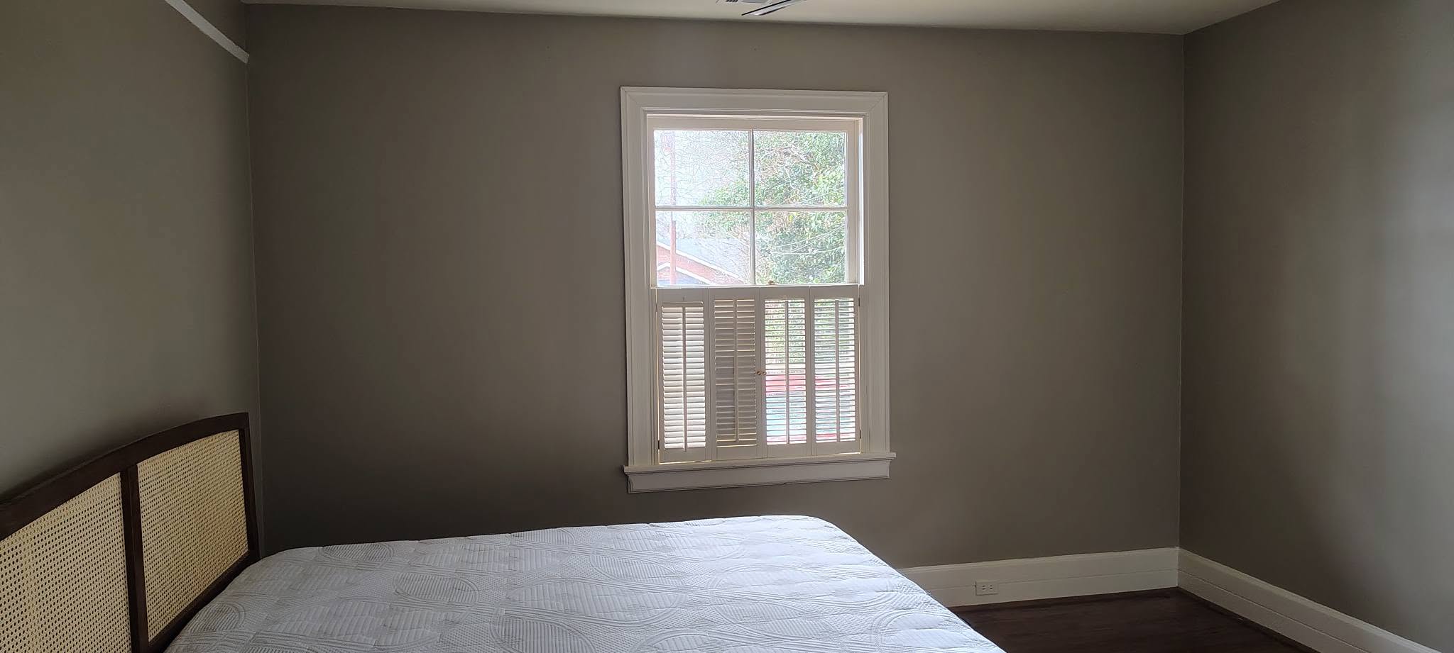 Bedroom with fresh paint, white shutters and dark hardwood floor