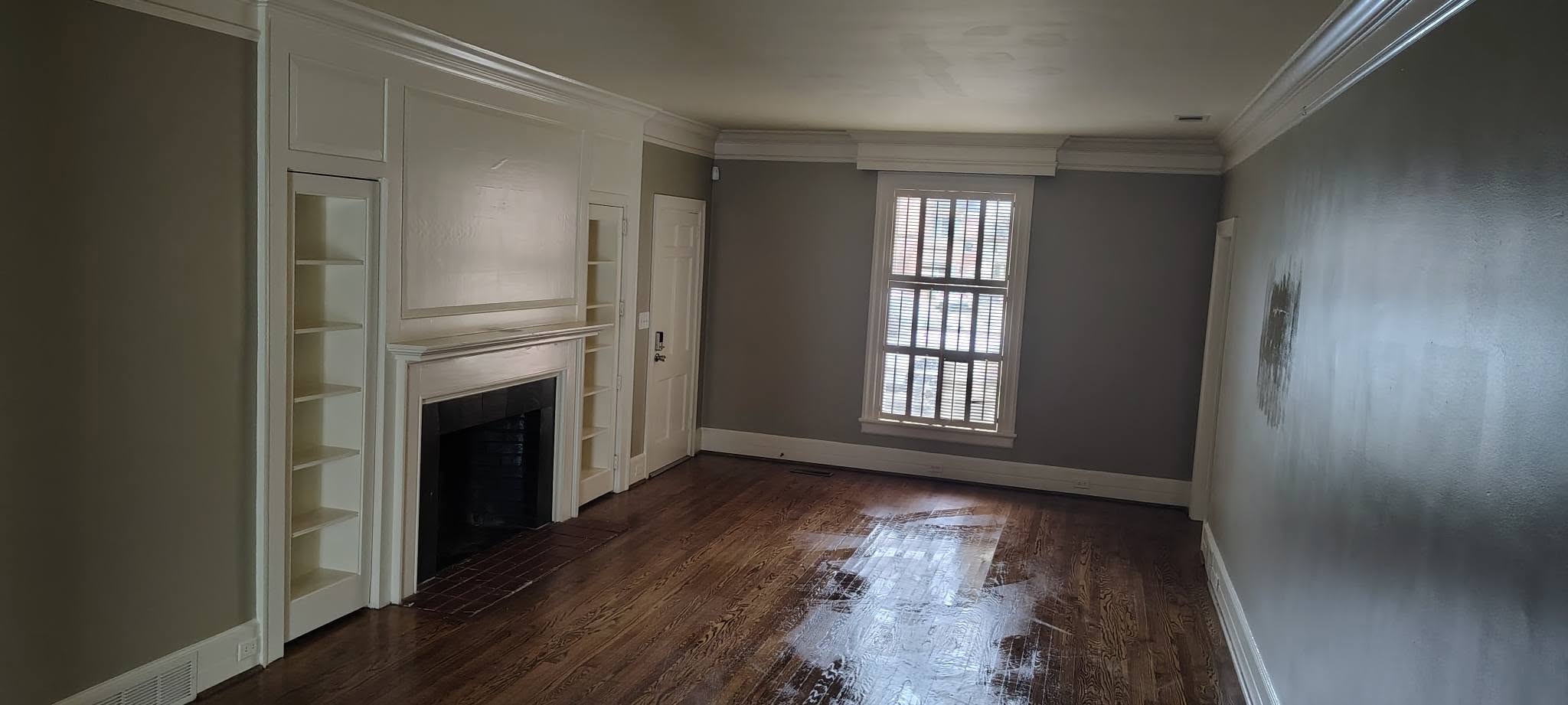 Living room with painted fireplace, built-ins and shutters